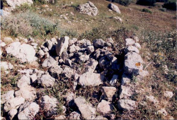 B : Le site fortifié d’Agz. Traces de murs arasés en pierre : les vestiges dessinent un angle droit attestant la présence à l’intérieur de la première enceinte du site, d’un local rectangulaire. Sa fonction reste inconnue.
